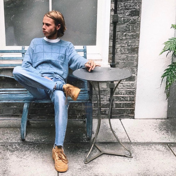 h clothing - picture of the founder Hugo sitting on a bench wearing blue