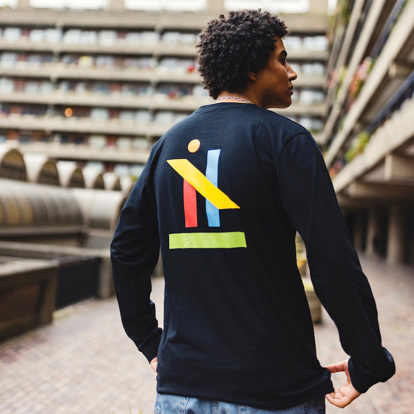 h clothing - male model with back to camera wearing black long sleeved tshirt with graphic of colourful geometric shapes