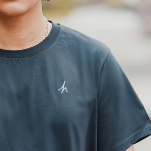 h clothing - close up of  model wearing black tshirt with blue h logo on left breast