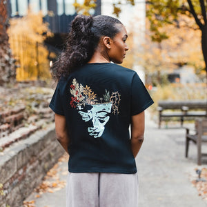 h clothing - female model with back to camera wearing black tshirt with graphic of a face and a garden on top of the head