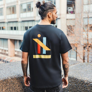 h clothing - male model with tattoos with back to camera wearing black tshirt with graphic of colourful geometric shapes