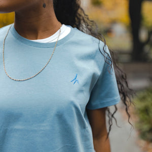 h clothing - close up of female model wearing blue grey tshirt with blue h logo on left breast