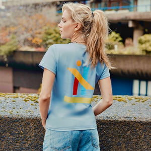 h clothing - female model with back to camera wearing grey blue tshirt with graphic of colourful geometric shapes
