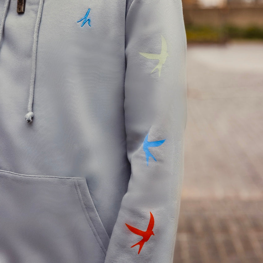 h clothing - close up of model wearing heather grey hoodie with colourful birds going down the left arm
