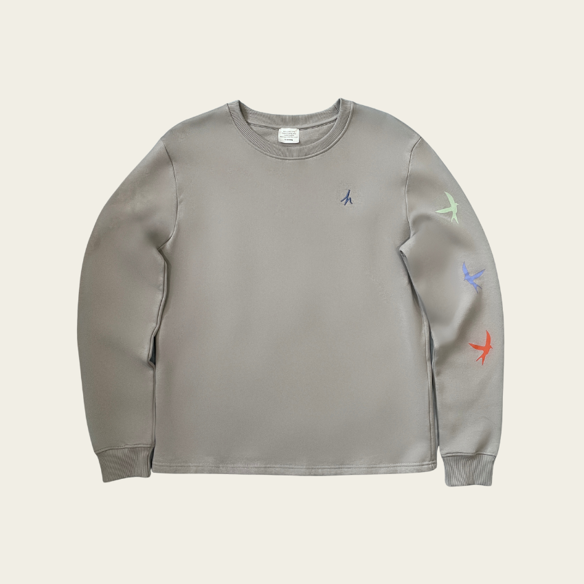 h clothing - flat shot of front of heather grey sweatshirt with blue h logo on left breast and colourful birds down the left arm