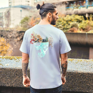 h clothing - male model with tattoos with back to camera wearing pastel grey tshirt with graphic of a face and a garden on top of the head