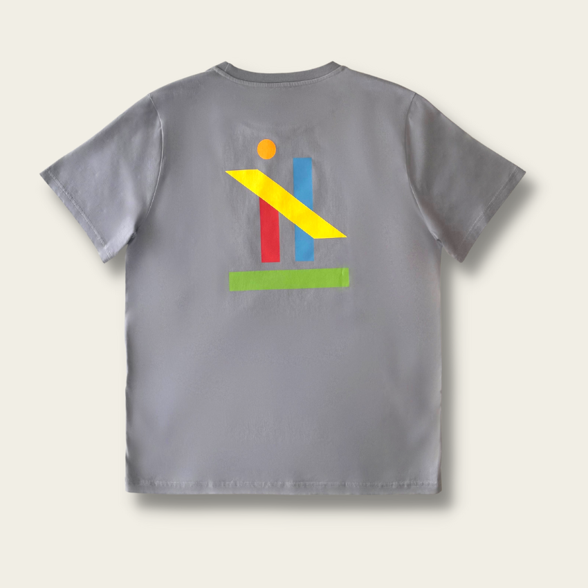 h clothing - flat shot of back of pastel grey tshirt with graphic of colourful geometric shapes