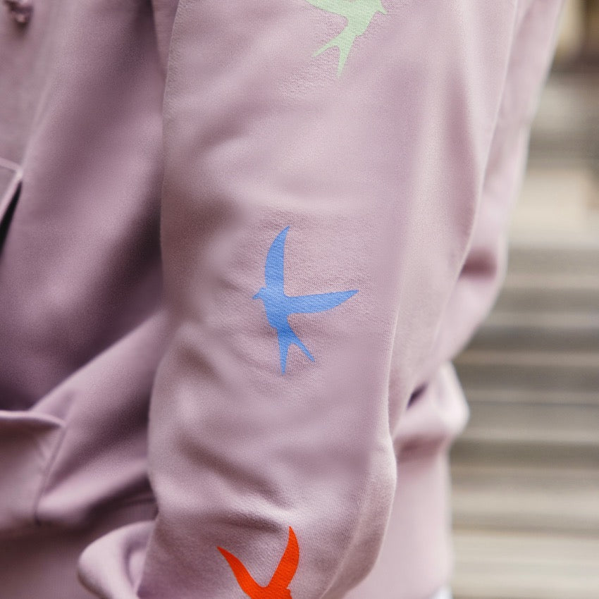 h clothing - close up of model wearing light purple hoodie with colourful birds going down the left arm