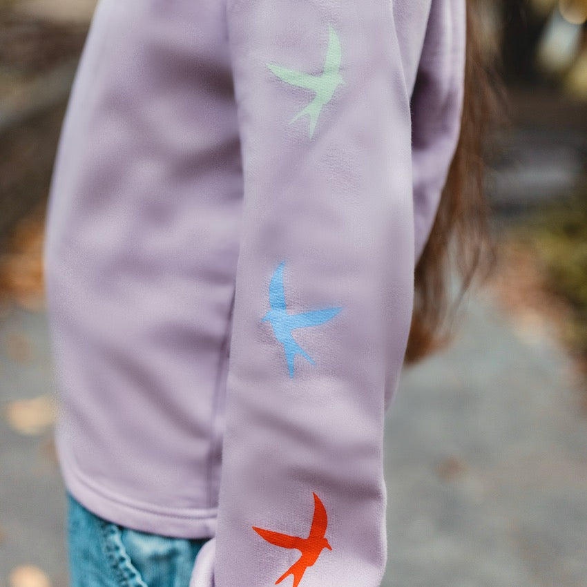 h clothing - close up of female model wearing light purple sweatshirt with colourful birds going down the left arm