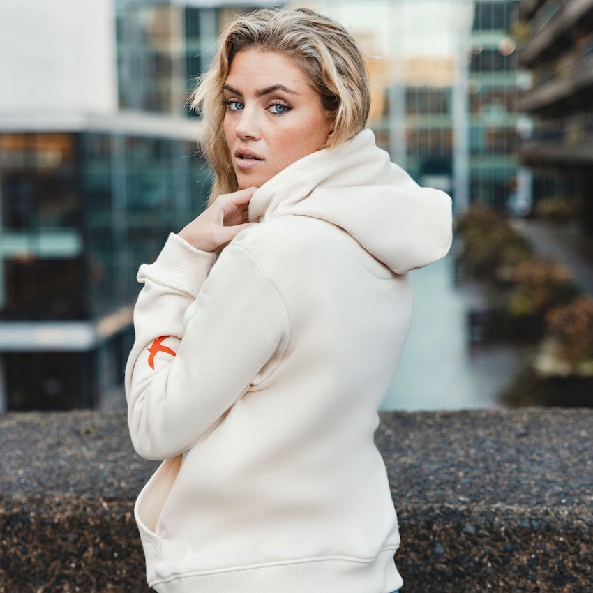 h clothing - female model with back to camera wearing off-white cream hoodie with red bird on left arm