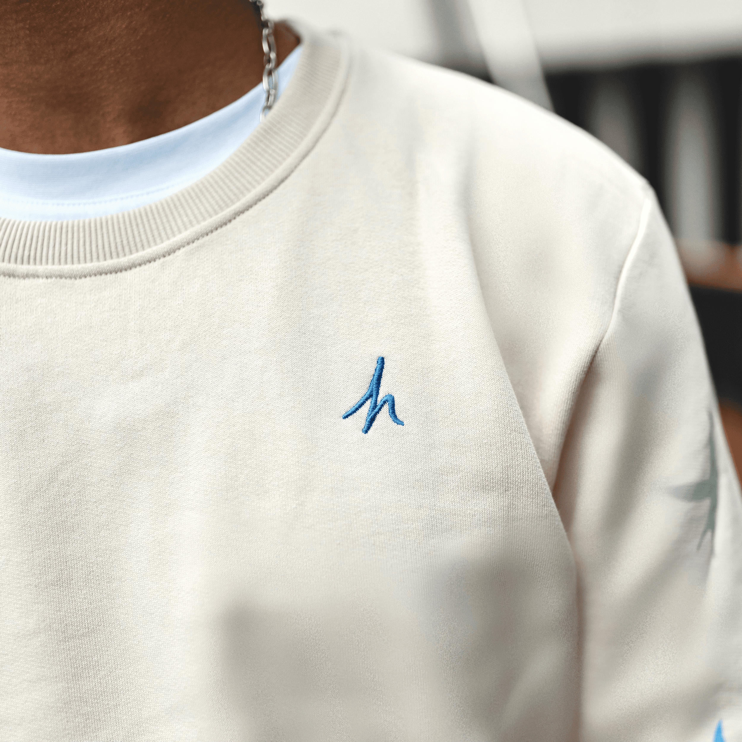 h clothing - close up of off-white cream sweatshirt with blue h logo