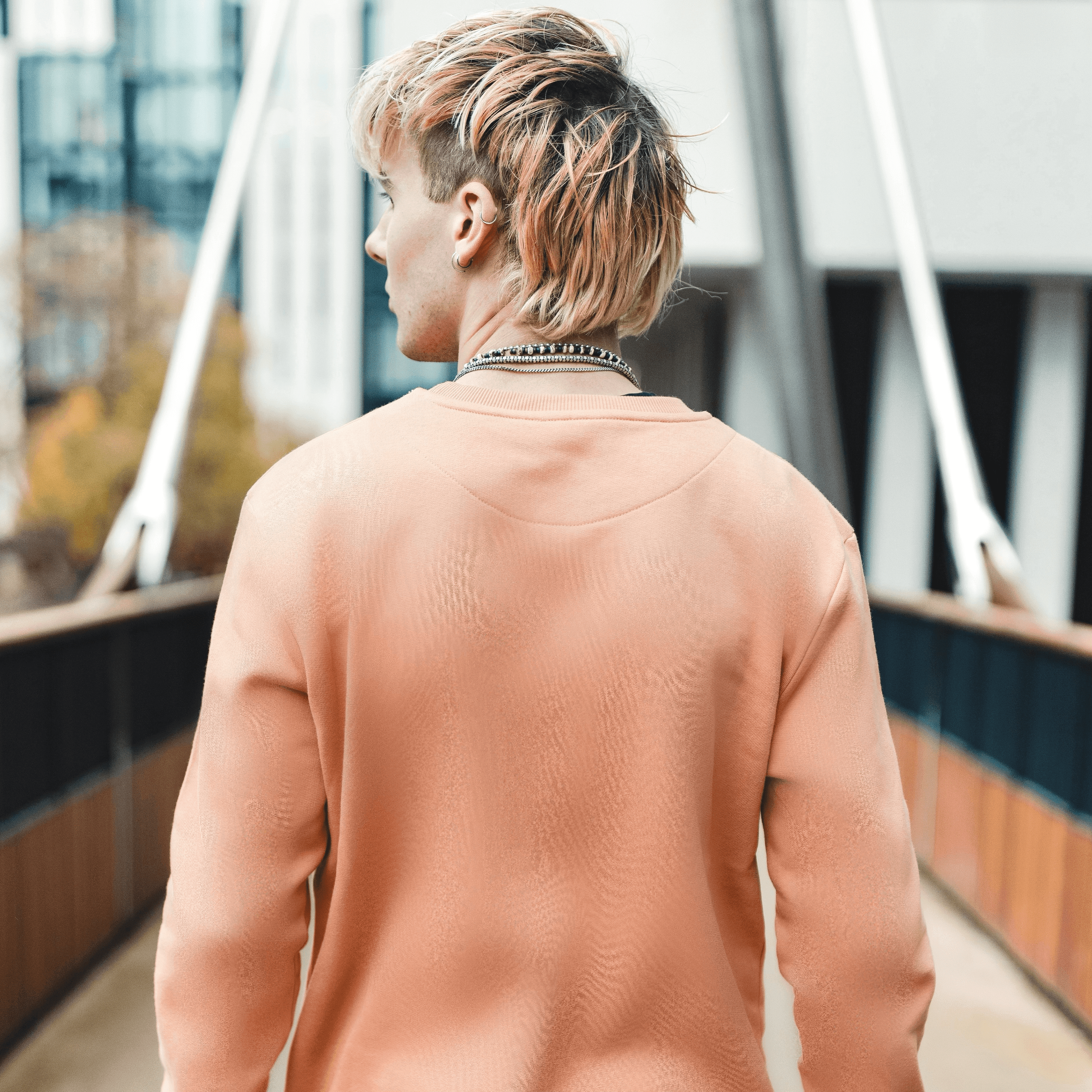 h clothing - male model with back to camera wearing pastel orange sweatshirt