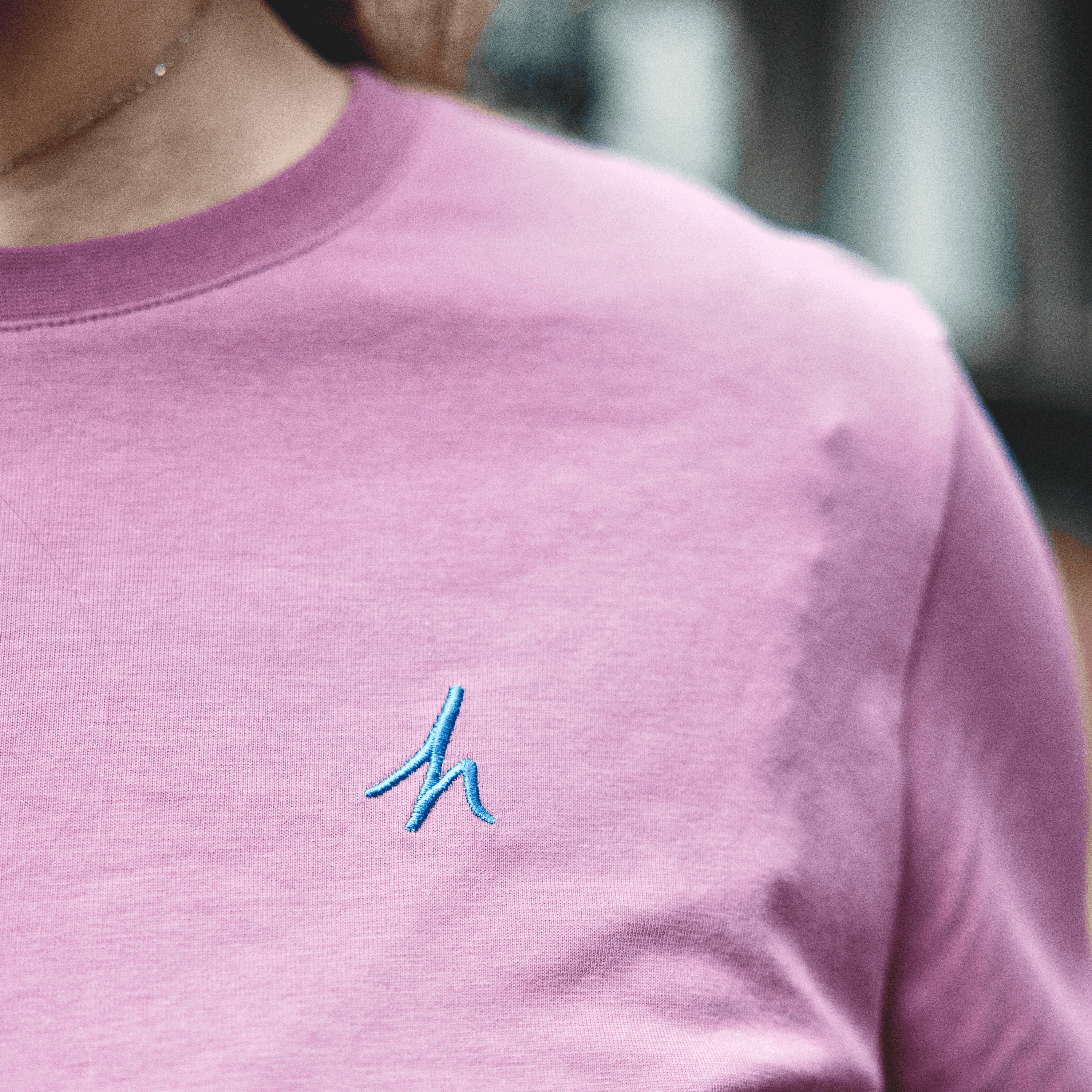 h clothing - close up of female model wearing pastel pink tshirt with blue h logo