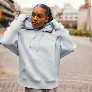 h clothing - female model facing the camera holding hood wearing sky blue hoodie