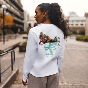 h clothing - female model with back to camera wearing white long sleeved tshirt with graphic of a face and a garden on top of the head