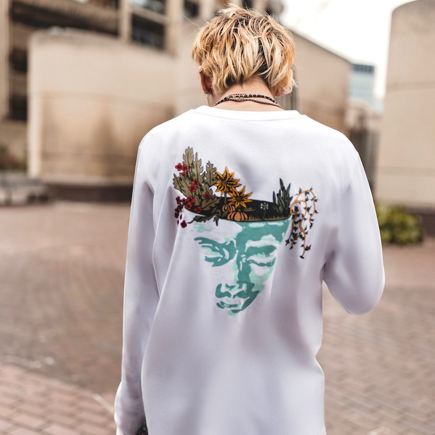 h clothing - male model with back to camera wearing white long sleeved tshirt with graphic of a face and a garden on top of the head
