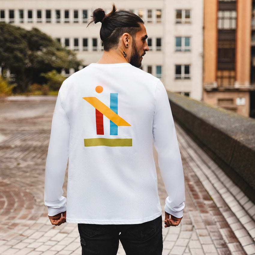 h clothing - male model with back to camera wearing white long sleeved tshirt with graphic of colourful geometric shapes