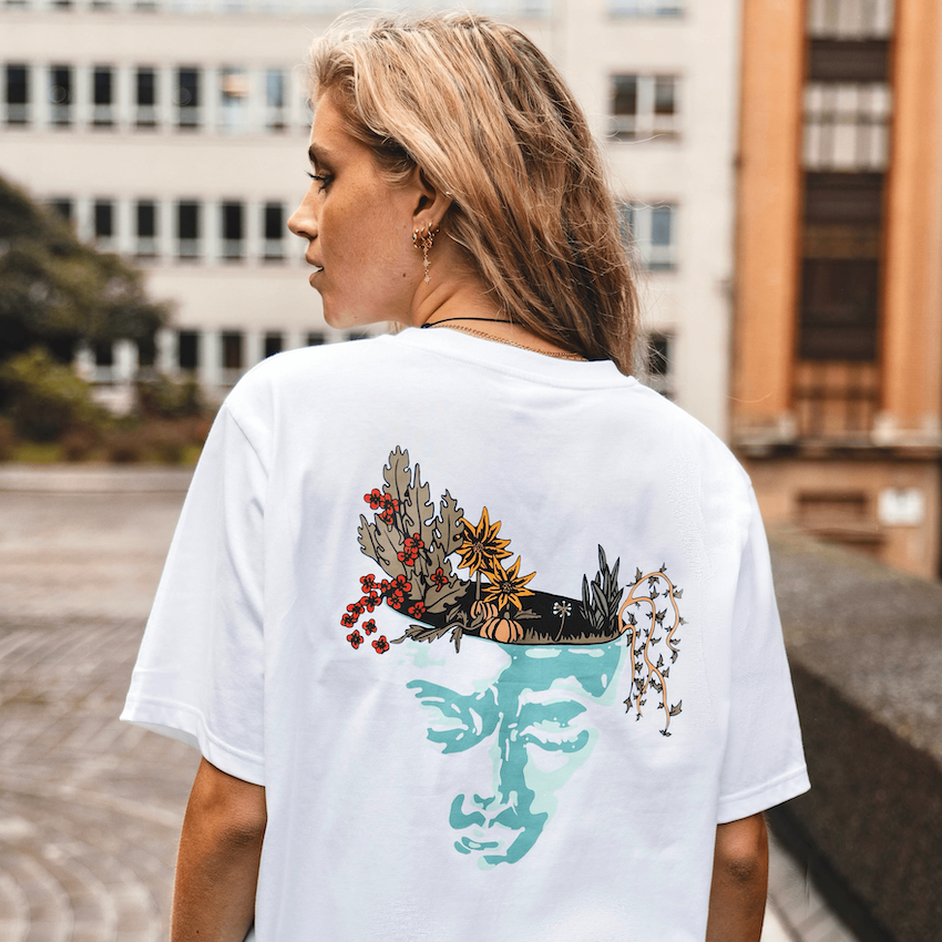 h clothing - female model with back to camera wearing white tshirt with graphic of a face and a garden on top of the head