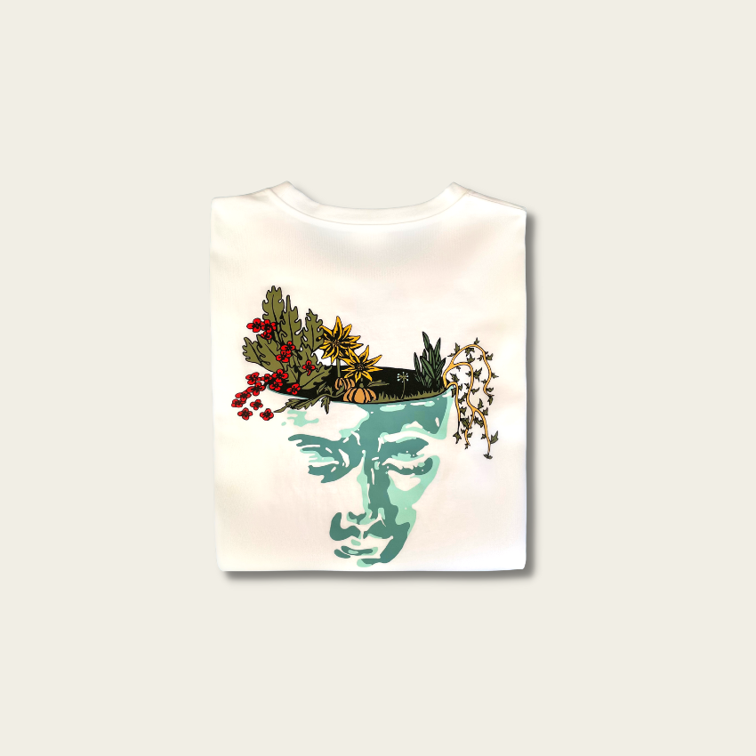 h clothing - flat shot of back of folded white tshirt with graphic of a face and a garden on top of the head